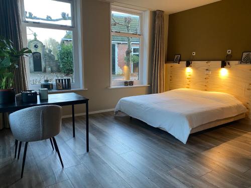 1 dormitorio con cama, escritorio y ventana en Bed and Breakfast Stinzenflora en Cornjum