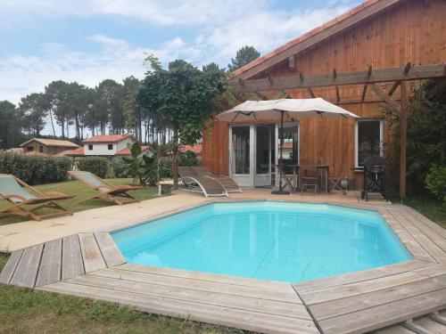 a swimming pool with a deck and a house at Maison moderne proche lac et plage in Léon