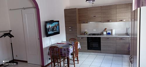 cocina con mesa con sillas y TV en Appartamento tra Como e Milano, en Bregnano