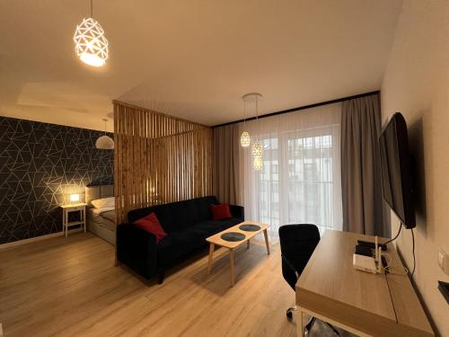 a living room with a black couch and a bedroom at Apartament Studio Centrum in Koszalin