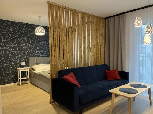 a living room with a blue couch and a bed at Apartament Studio Centrum in Koszalin