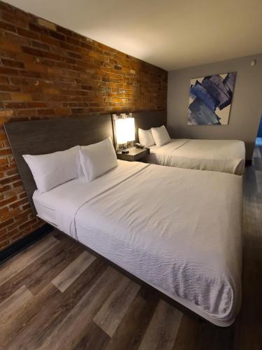 two beds in a hotel room with a brick wall at Travelodge by Wyndham Barrie in Barrie