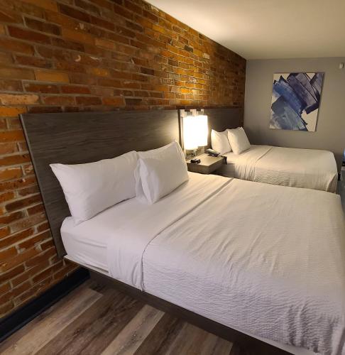 two beds in a room with a brick wall at Travelodge by Wyndham Barrie in Barrie