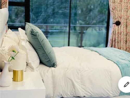 a bed with white sheets and pillows on a table at Ndaba Golf Lodge on 13th hole in East London