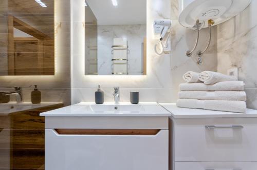 ein weißes Badezimmer mit einem Waschbecken und einem Spiegel in der Unterkunft Apartment Papillon 5 in Zlatibor