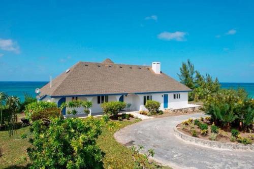 a house on the beach with the ocean in the background at Tourmaline home in Governorʼs Harbour