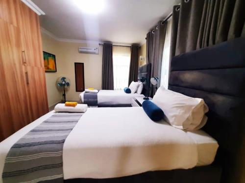 two beds in a hotel room with white and blue at InstaHomes by Tru - Villa in Blantyre
