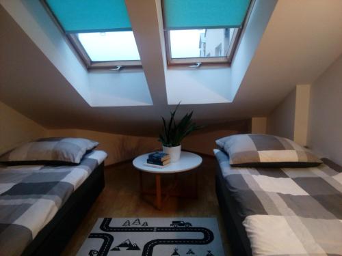 a attic room with two beds and a table at Leśny Loft in Gdynia