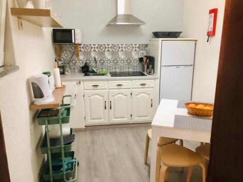 uma pequena cozinha com armários brancos e uma mesa em Casa Nunes 2 em Pinhão