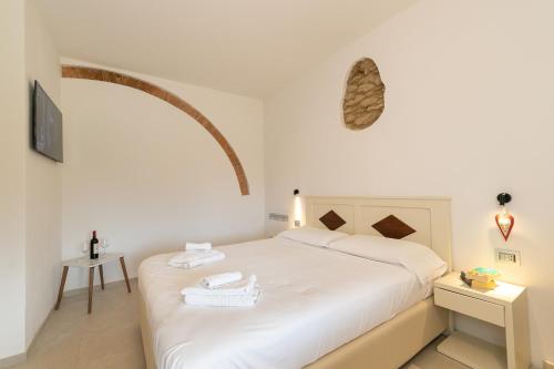 a bedroom with a white bed with an arch above it at Garden Relais Le Fontanelle in Montescudaio