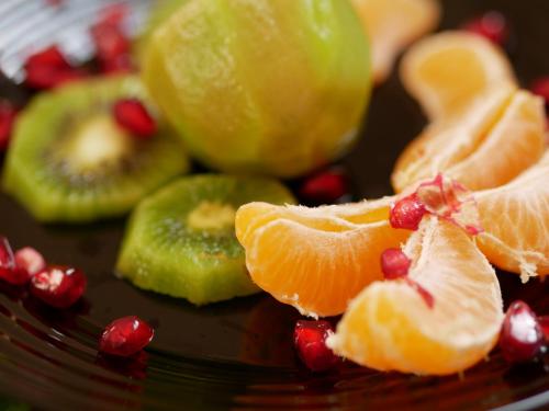 a plate of fruit with oranges and pomegranates at Altavista mountain apartment in Samokov