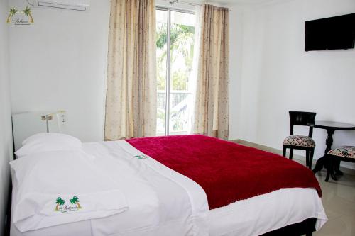 um quarto com uma cama branca e um cobertor vermelho em Centro Vacacional Las Palmas em San José del Guaviare
