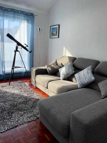 a living room with a couch and a telescope at Penthouse Palmeira in Gaula