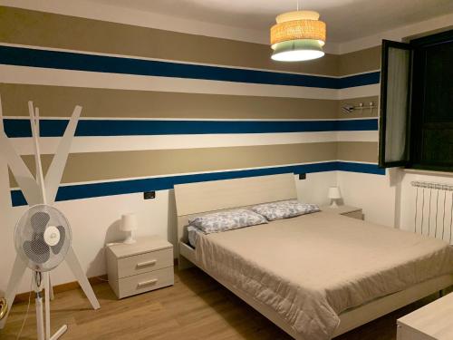 a bedroom with striped walls and a bed and a fan at Iseo Lake apartment in Sulzano