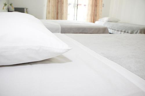 a bed with white sheets and a pillow on it at Centro Vacacional Las Palmas in San José del Guaviare
