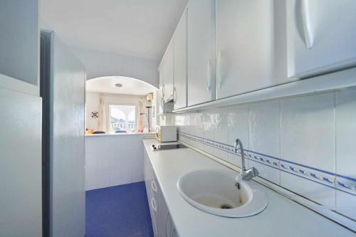a white bathroom with a sink and a mirror at Apartamento Balcón de San José, piscina, parking in San José