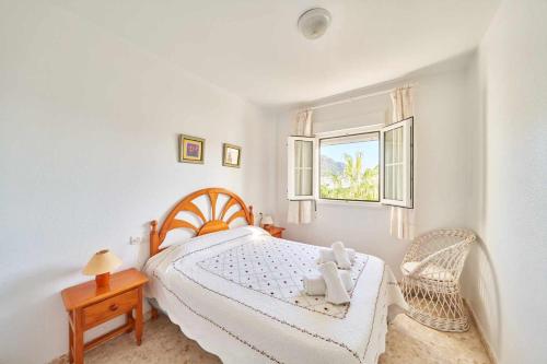 a white bedroom with a bed and a window at Apartamento Balcón de San José, piscina, parking in San José
