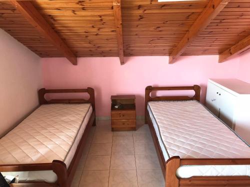 two beds in a small room with wooden ceilings at Ion Apartments Messolonghi Double Room Sea View Loft in Mesolongion
