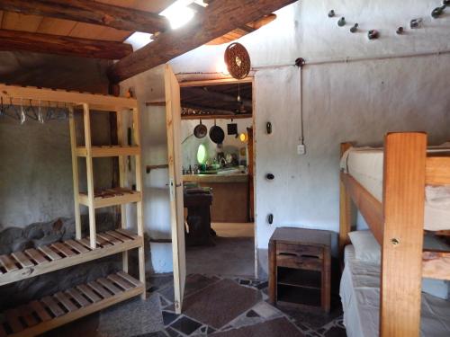 a room with two bunk beds and a kitchen at Ecohostel Tay Pichin in San Marcos Sierras