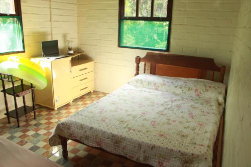 um quarto com uma cama e uma secretária com um computador portátil em Casa de Campo - Sítio da tia Vera em Maquiné