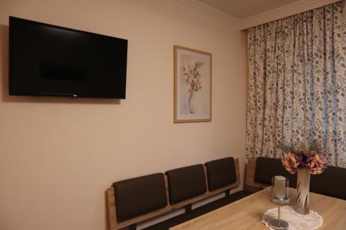 a dining room with a table and a flat screen tv at Landhaus-Appartements Warraich in Schladming