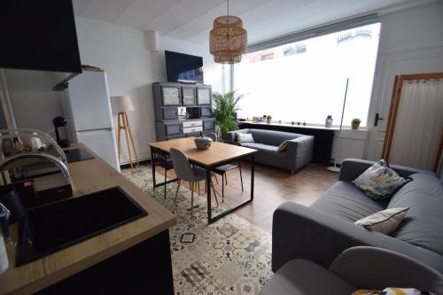 uma sala de estar com um sofá azul e uma mesa em La Maison du Bonheur - Lille em Lille