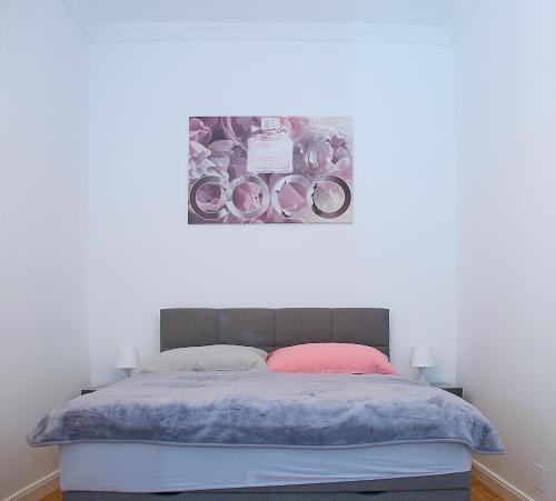 a bedroom with a bed with a painting on the wall at Pink Lotus Apartment in Vienna