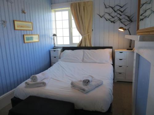 Un dormitorio con una cama blanca con toallas. en Coastguard Lookout, en Hunstanton