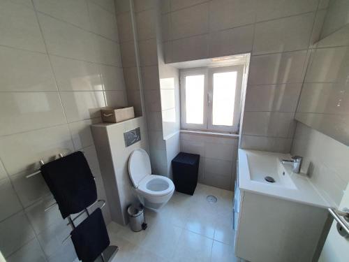 La salle de bains blanche est pourvue de toilettes et d'un lavabo. dans l'établissement Holidays House, à São Martinho do Porto