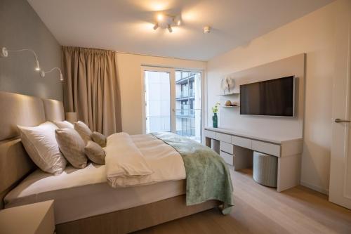 a bedroom with a bed with a desk and a television at The Sailor, full sea view, use of hotel swimming pool and sauna in Cadzand