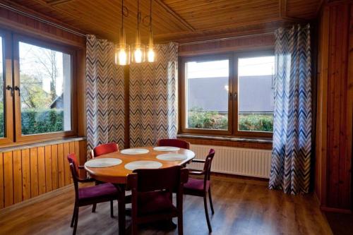 uma sala de jantar com mesa, cadeiras e janelas em Janosik em Kluszkowce