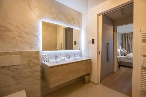 een badkamer met een wastafel en een spiegel bij The Sailor, full sea view, use of hotel swimming pool and sauna in Cadzand