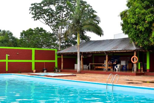 - une piscine en face d'un bâtiment avec une maison dans l'établissement Palmas Park Hotel y Restaurant, à Obligado