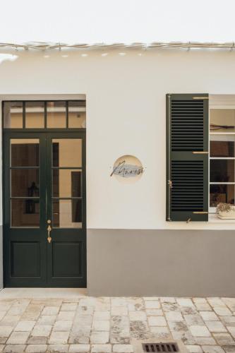a green door and a window on a white wall at Marosi Boutique Hotel in Ciutadella