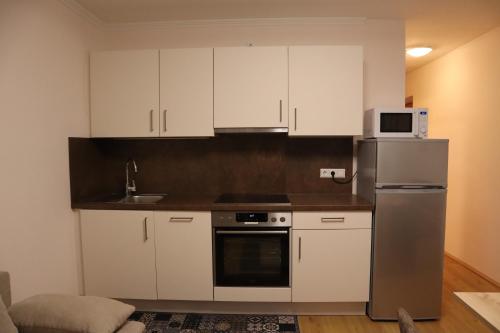 a kitchen with white cabinets and a stainless steel refrigerator at Landhaus-Appartements Warraich in Schladming