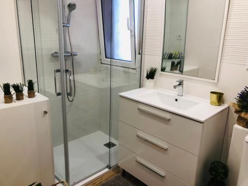 uma casa de banho com um lavatório e um chuveiro em Precioso apartamento en Los Castros em Santander
