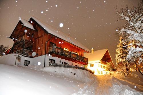 a large wooden building in the snow at night at Ferienhof Margarethengut in Unterach am Attersee