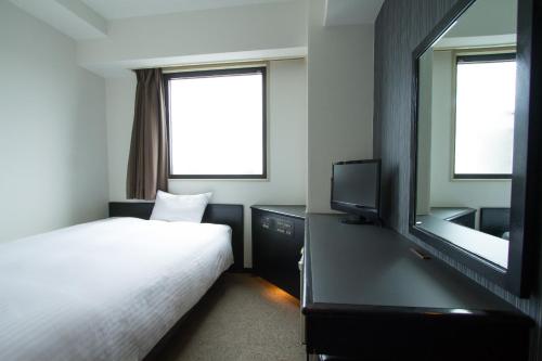 um quarto com uma cama, uma televisão e um espelho em Green Rich Hotel Oita Miyakomachi em Oita