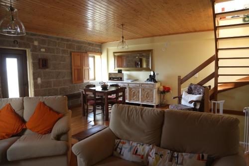 a living room with a couch and a kitchen with a table at Casa d'Avó Serra da Estrela in Seia