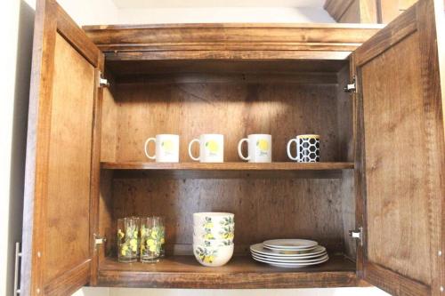 a cabinet with cups and plates and mugs in it at Casa Mezquite. In Downtown Brownsville in Brownsville