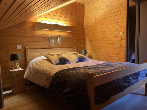 ein Schlafzimmer mit einem Bett und einer Holzwand in der Unterkunft Chalet Les Sapins sauna au pied des pistes in La Bresse