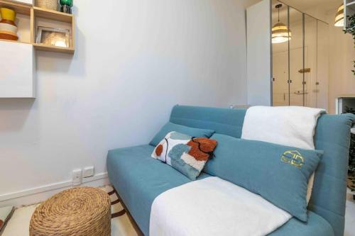un sofá azul con un animal de peluche en una habitación en Studio de charme à 2 pas de Paris, en Malakoff