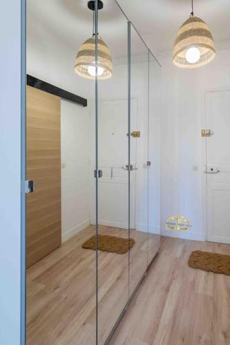a bathroom with a glass shower with two lights at Studio de charme à 2 pas de Paris in Malakoff