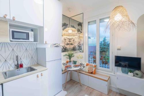 eine Küche mit einer Spüle, einer Mikrowelle und einem Fenster in der Unterkunft Studio de charme à 2 pas de Paris in Malakoff