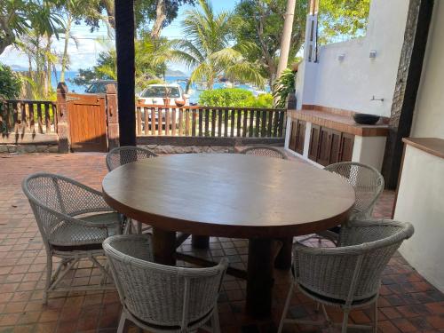 einen Holztisch und Stühle auf einer Terrasse in der Unterkunft Praia dos Ossos Guest House - Búzios com pé na areia in Búzios