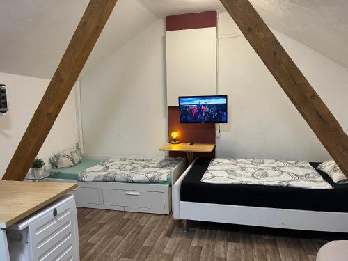 two beds in a room with a tv on the wall at Monteurzimmer bei EnergyFreund in Knetzgau