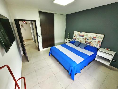 Schlafzimmer mit einem Bett mit blauer und weißer Bettwäsche in der Unterkunft Casa en Barrio privado Luján in Ciudad Lujan de Cuyo