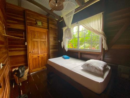 a small bed in a room with a window at True Nature Jungle House in Bastimentos