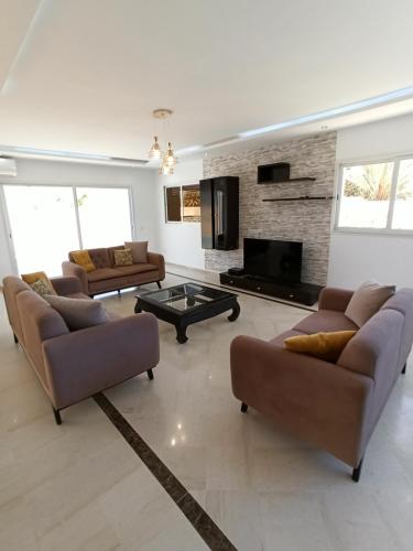 una gran sala de estar con sofás y chimenea. en Magnifique villa avec piscine, en Djerba