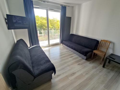 uma sala de estar com um sofá e uma janela em 1110 Śmiałego 39 - Tanie Pokoje w Apartamencie - samodzielne zameldowanie - self check in em Poznań